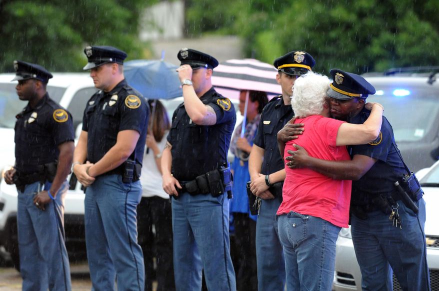 A woman hugs an officer during the procession for the body of Hattiesburg Police Officer Benjamin Deen, Monday, May 11, 2015, in Hattiesburg, Miss. Marvin Banks faces two counts of capital murder in the Saturday shootings of Officers Deen and Liquori Tate following a traffic stop. (Eli Baylis/The Hattiesburg American via AP) NO SALES