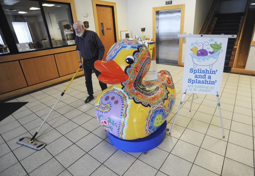 City of St. Joseph employee Art Pearce sweeps up around the newest art sculpture on display at City Hall in St. Joseph, Mich., Thursday, Feb. 5, 2015. The piece "Paisley Duck," by artist Betsy Kerr Reif, is part of this summer's public art display titled "Splishin' and a Splashin," on display May 15-September 24, 2015, throughout the downtown area. (AP Photo/The Herald-Palladium, Don Campbell)