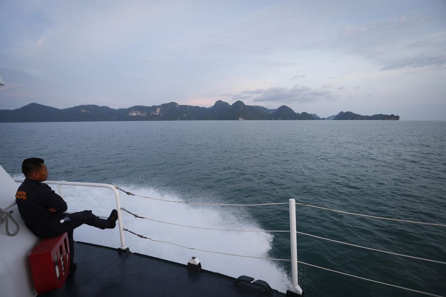 Malaysia's maritime enforcement agency official rest on their patrolling boat along the coast of Langkawi Island, Malaysia, on Tuesday, May 12, 2015. A crisis involving boatloads of Rohingya and Bangladeshi migrants stranded at sea deepened Tuesday as Malaysia said it would turn away any more of the crowded, wooden vessels unless they were sinking. (AP Photo/Vincent Thian)