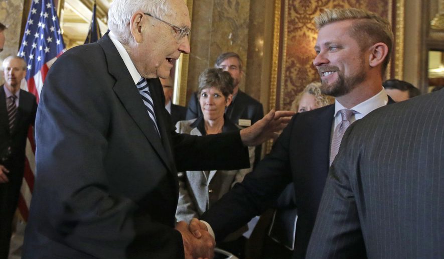 FILE - In this March 4, 2015, file photo, Elder L. Tom Perry, left, of the Church of Jesus Christ of Latter-day Saints Quorum of the Twelve Apostles shakes hands with Equality Utah executive director Troy Williams after Utah lawmakers introduced a landmark anti-discrimination bill during a news conference at the Utah State Capitol, in Salt Lake City. A Mormon church-backed antidiscrimination law that protects gay and transgender people and religious rights has taken effect amid skepticism from some LGBT residents. (AP Photo/Rick Bowmer, File)