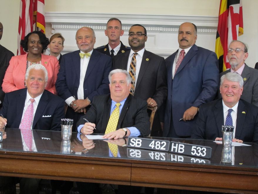 Billy Murphy, an attorney who represents the family of Freddie Gray, stands between Senate President Thomas V. Mike Miller, seated far left, and Gov. Larry Hogan, center, as Hogan signs a bill to create a commission to study the implementation of police body cameras, Tuesday, May 12, 2015 in Annapolis, Md. Murphy said: The bills Hogan is signing Tuesday were approved before the death of Freddie Gray, who was fatally injured in Baltimore police custody last month. (AP Photo/Brian Witte)