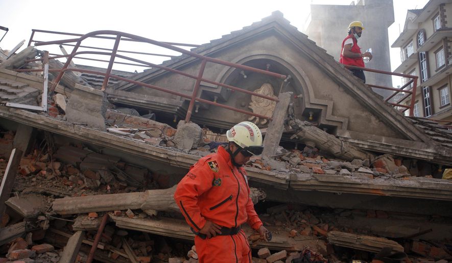 A Mexican rescue worker stands at the site of a building that collapsed in an earthquake in Kathmandu, Nepal, Tuesday, May 12, 2015. A major earthquake has hit Nepal near the Chinese border between the capital of Kathmandu and Mount Everest less than three weeks after the country was devastated by a quake. (AP Photo/Niranjan Shrestha)