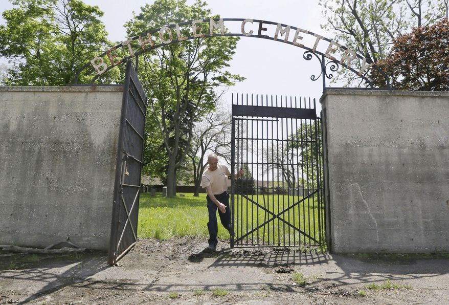 In a photo from Sunday, May 10, 2015, in Hamtramck, Mich., Gino Cardillo closes the gates of the Beth Olem Cemetery on the grounds of the General Motors Co.'s Detroit Hamtramck Plant. For plant security, public access is limited to a couple days a year, typically Sundays nearest to the Jewish holidays of Rosh Hashanah and Passover, and some special events. (AP Photo/Carlos Osorio)