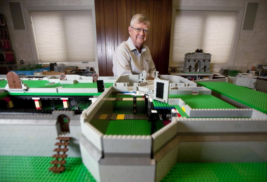 In this March 25, 2015 photo, retired dermatologist Dr. Robert Carney Jr., of Decatur, Ill., sits behind the early stages of a LEGO replica of Caernarfon Castle. The Welsh government commissioned Carney to build the castle after seeing his work on other LEGO castles. (Danny Damiani/Herald & Review via AP)