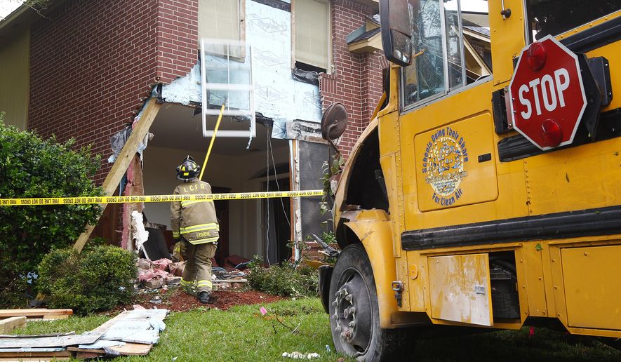 A League City firefighter works to stabilize debris after a Clear Creek ISD special education bus was removed after crashing in to the front of a house in the Oaks of Clear Creek neighborhood on Tuesday, May 12, 2015 in League City, Texas. The driver, an aide and an 11-year-old student were on board at the time of the crash and were all transported to the hospital with minor injuries. Sgt. Tammy Spencer says a woman and her three children were in the house but not injured. (AP Photo/The Galveston County Daily News, Kevin M. Cox) MANDATORY CREDIT, NO SALES, TV OUT