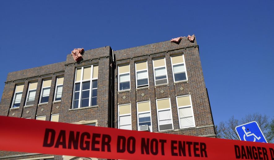 In this photo taken Tuesday, May 12, 2015, a line of "Danger" tape blocks the entrance of South Central Calhoun High School in Lake City, Iowa, as pieces of insulation hang from the roof. Students were allowed back into the building Tuesday to retrieve all their items following Sunday's tornado. (Peter Kaspari/The Messenger via AP)