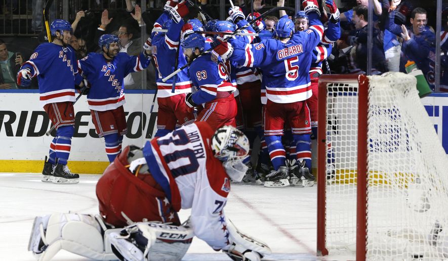The New York Rangers celebrate the game winning goal by center Derek Stepan (21) against the Washington Capitals as Capitals goalie Braden Holtby looks at the puck in the net in overtime of Game 7 of the Eastern Conference semifinals during the NHL hockey Stanley Cup playoffs, Wednesday, May 13, 2015, in New York. The Rangers won 2-1. (AP Photo/Kathy Willens)