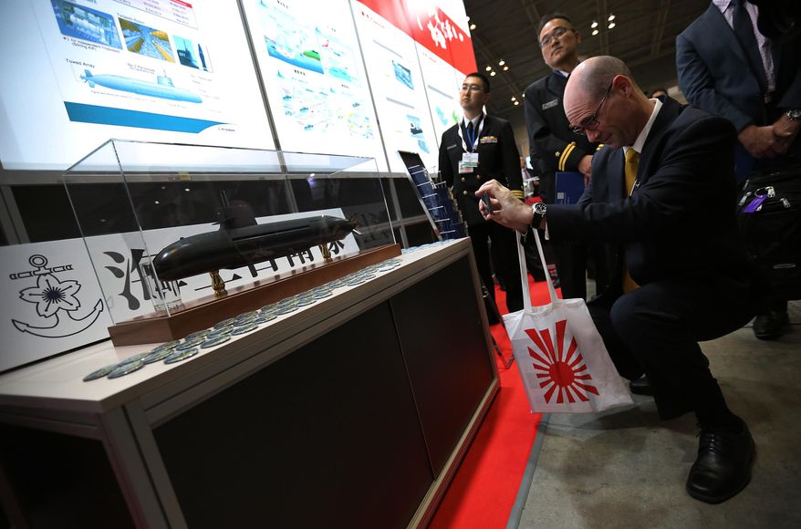 A visitor takes photo of a scale model of a Japanese Maritime Self Defense Force Soryu-class submarine at a first-ever defense industry fair in Yokohama, Wednesday, May 13, 2015. A year after Japan eased a longstanding ban on military exports, barely a trickle of deals has formed for its powerhouse manufacturers who are reckoning with latecomer status in a crowded global industry. (AP Photo/Eugene Hoshiko)