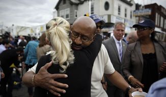 Philadelphia Mayor Michael Nutter, center right, hugs Lori Dee Patterson, a nearby resident, after she handed him a cup of coffee after he spoke at a news conference near the scene of a deadly train derailment, Wednesday, May 13, 2015, in Philadelphia. An Amtrak train headed to New York City derailed and crashed in Philadelphia on Tuesday night, killing at least six people and injuring dozens more. (AP Photo/Matt Slocum)