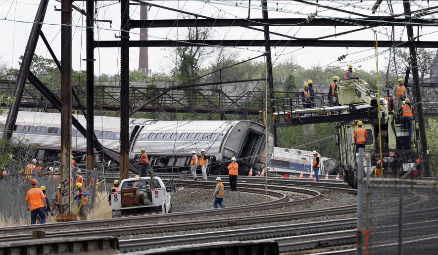 Emergency personnel walk near the scene of a deadly train wreck, Wednesday, May 13, 2015, in Philadelphia. Federal investigators arrived Wednesday to determine why an Amtrak train jumped the tracks in Tuesday night's fatal accident. (AP Photo/Mel Evans)