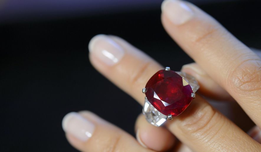 FILE - This May 6, 2015 file photo shows a Sotheby's employee wearing a ruby and diamond ring by Cartier, with a Burmese ruby weighing 25.59 carats, during a preview at the Sotheby's auction house in Geneva, Switzerland. The ring sold for $30.3 million at auction, Tuesday, May 12, setting a world auction record for any ruby and for any stone by Cartier, according to Sotheby's. (Martial Trezzini/Keystone via AP, File)