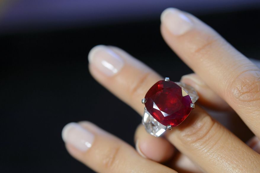 FILE - This May 6, 2015 file photo shows a Sotheby's employee wearing a ruby and diamond ring by Cartier, with a Burmese ruby weighing 25.59 carats, during a preview at the Sotheby's auction house in Geneva, Switzerland. The ring sold for $30.3 million at auction, Tuesday, May 12, setting a world auction record for any ruby and for any stone by Cartier, according to Sotheby's. (Martial Trezzini/Keystone via AP, File)