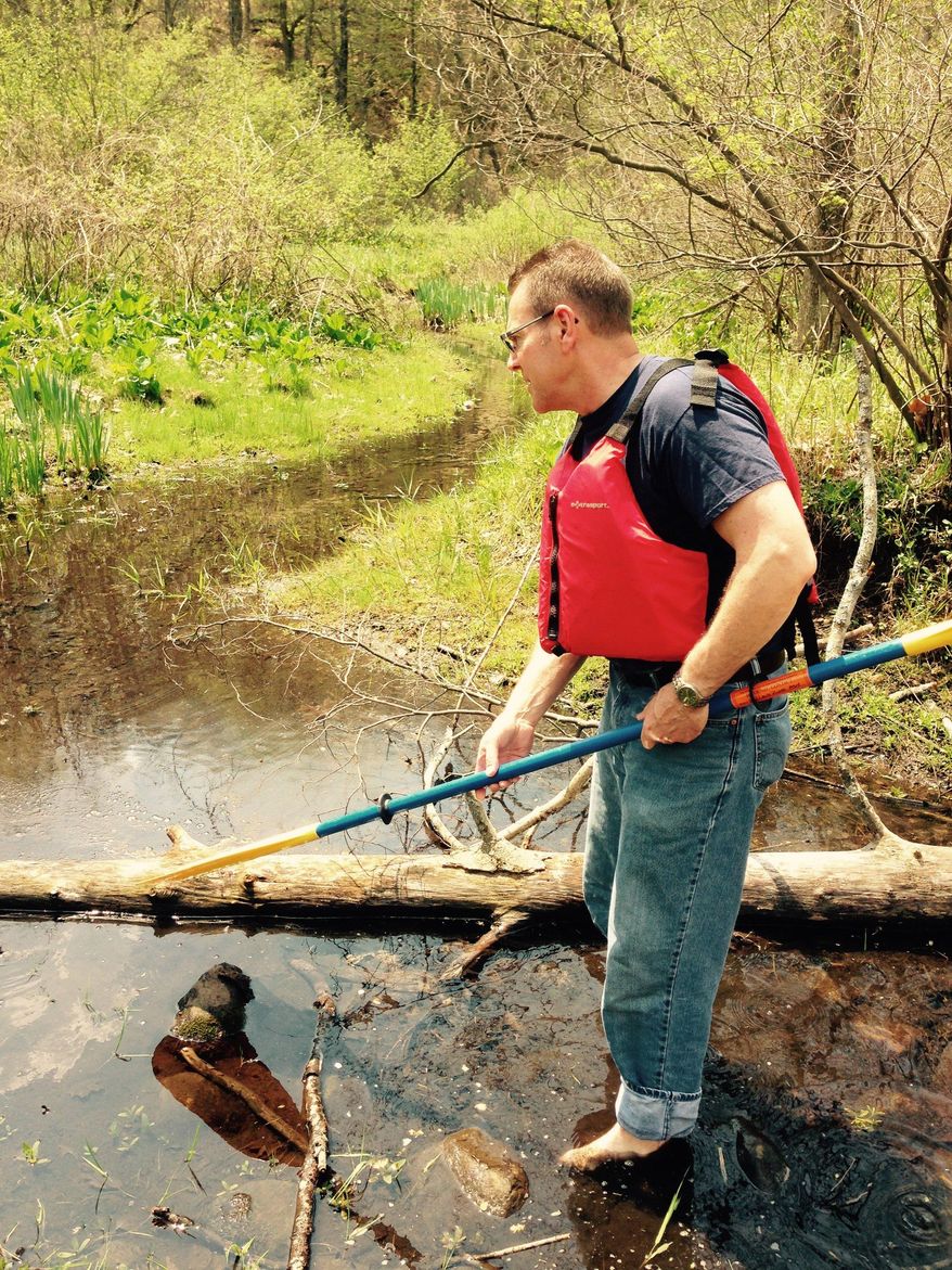 In this photo taken Thursday, May 7, 2015, Mark Ducharme, of the Michigan Department of Environmental Quality, shows where some oil remains in the ground in a wetland next to the Kalamazoo River in Calhoun County, Mich. An Enbridge Inc. pipeline ruptured in 2010, spilling more than 800,000 gallons of crude oil into Talmadge Creek and the river. The state of Michigan and Enbridge Energy have filed a settlement related to the spill. Enbridge has agreed to restore or create 300 acres of wetlands in the Kalamazoo River watershed in southwestern Michigan (AP Photo/Edward J. White)
