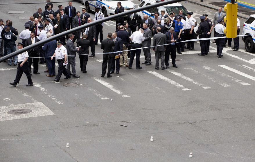 A hammer, bottom center between three white cups, lies in the middle of a Manhattan intersection as police investigators gather, Wednesday, May 13, 2015, after a man apparently wielding the hammer was shot and wounded by police in New York. The shooting took place shortly after 10 a.m. Wednesday blocks from Madison Square Garden and Penn Station in Manhattan. (AP Photo/Mark Lennihan)