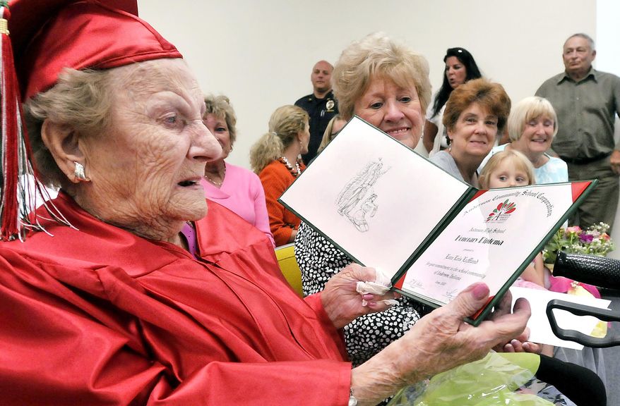 Wearing her cap & gown Lora Lois LeMond White Hardy, 99, looks over the honorary diploma from Anderson High School in Anderson, Ind. she received Tuesday May 12, 2015 from the Anderson Community Schools board of trustees. Lora, who turns 100 on May 28, had to quit school her senior year in 1933 just four credits shy of her diploma to go to work to help support her family. (AP Photo/The Herald Bulletin, John P. Cleary)