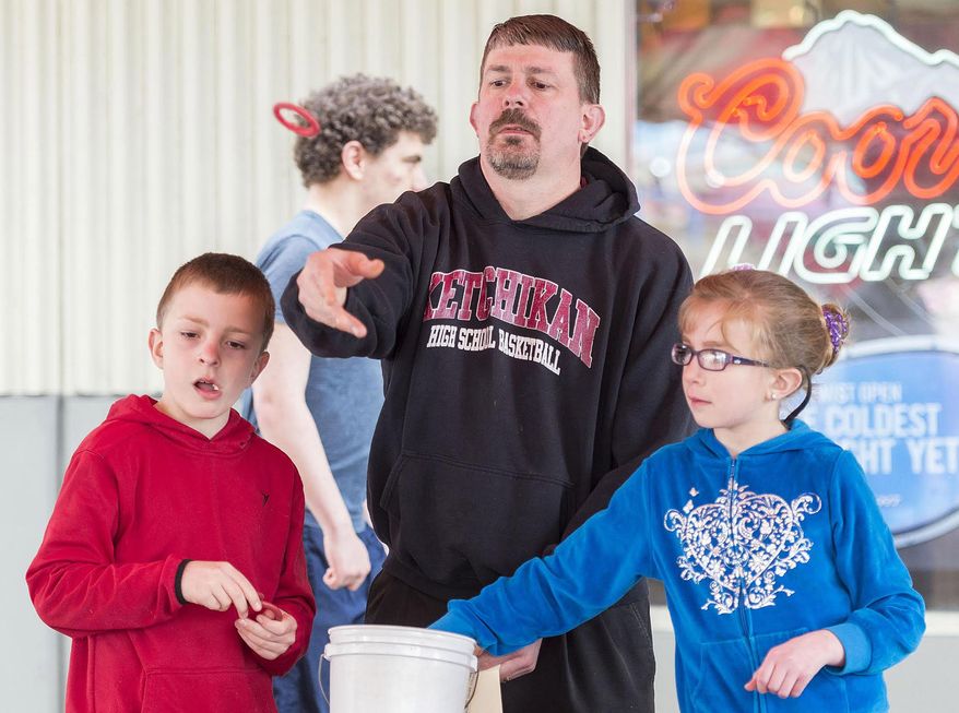 ADVANCE FOR SATURDAY MAY 16 AND THEREAFTER - In this May 3, 2015 photo, Ketchikan High School boy's basketball coach Eric Stockhausen, center, plays ring toss with his children, Marcus, left, 8, and Ella, 10, at the Golden Wheel Amusements' Alaska Spring Carnival in Ketchikan, Alaska. Golden Wheel Amusements was founded by family matriarch Claire Morton in 1967 and has been the only carnival company in Alaska for the past 49 years. (Taylor Balkom/Ketchikan Daily News via AP)