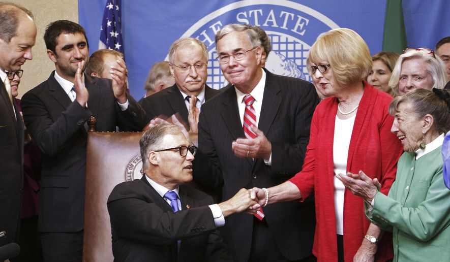 Gov. Jay Inslee shakes the hand of Nancy Reuter after the governor signed a bill named for her son, who was suicidal when he was killed in a police standoff, Thursday, May 14, 2015, in Olympia, Wash. "Joel's Law" allows family members to ask a judge to review cases whenever a mental health professional decides against detaining someone who could be a danger to themselves or others. (AP Photo/Rachel La Corte)