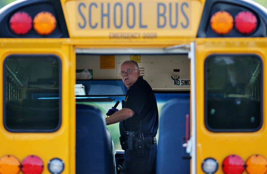 Police investigate the scene of a shooting involving a school bus Thursday, May 14, 2015, in Jacksonville, Fla. Authorities are looking for people suspected of shooting at the bus and injuring students. (Will Dickey/The Florida Times-Union via AP)