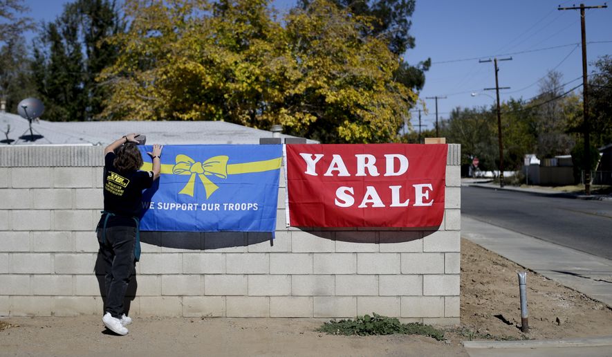 Volunteer Rose Sliepka removes a flag after a yard sale held to benefit Jerral Hancock, a 27-year-old Iraq war veteran who lost his left arm and was paralyzed from the waist down in a bomb explosion in Iraq, on Saturday, Oct. 26, 2013, in Lancaster, Calif. When the seniors in Jamie Goodreau's high school history class learned Hancock was once stuck in his modest mobile home for months when his handicapped-accessible van broke down, they decided to build him a new house from the ground up. It would be their end-of-the-year project to honor veterans, something Goodreau's classes have chosen to do every year for the past 15 years. (AP Photo/Jae C. Hong)