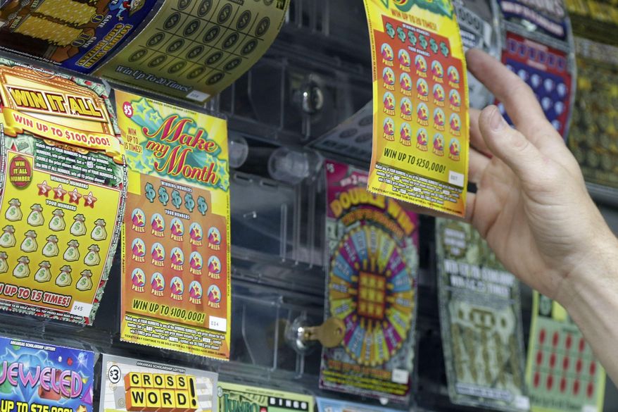 A gas station employee reaches for a lottery ticket in Little Rock, Ark., Thursday, May 14, 2015. On Thursday, a legislative committee overseeing the Arkansas lottery meets for the first time since the independent commission running the games was abolished. (AP Photo/Danny Johnston)