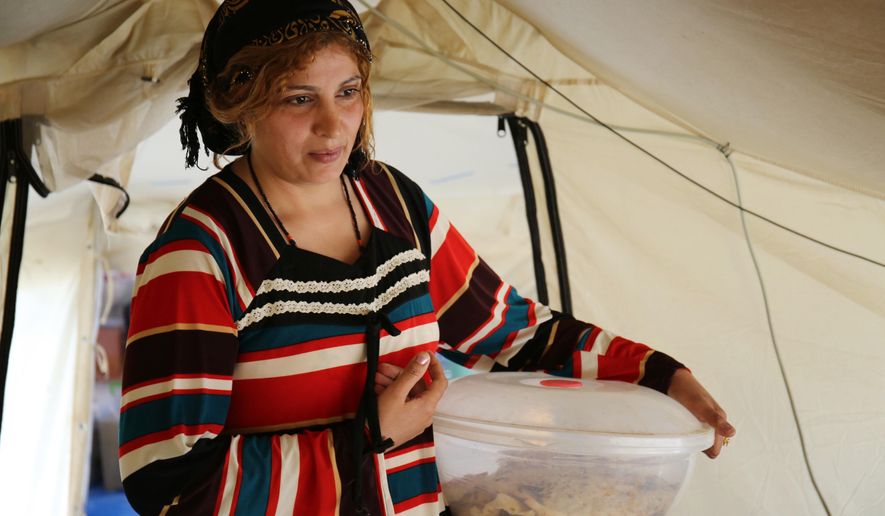 In this photo taken on Saturday, March 28, 2015, Muntaha Salih Khalaf, an Iraqi woman from Mosul, carries bread for her family at the Baharka camp for Iraqi displaced people outside of Irbil, Iraq. Decades of war and international sanctions have left millions of Iraqis traumatized after seeing loved ones killed or being uprooted from their homes. The medical infrastructure in the country, however, is ill-served to treat them. The situation has been exacerbated by the latest wave of fighting in the north, which has displaced tens of thousands of Sunnis, Kurds, and Yazidis, sending new flows of traumatized people into overcrowded camps for the displaced. (AP Photo/ Maeva Bambuck)