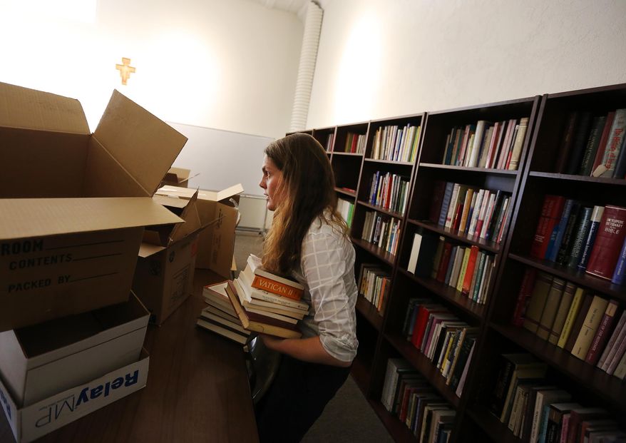 Wyoming Catholic College librarian Hillary Rowney files stacks of newly-donated books that were left to the school by a priest on Friday afternoon, April 17, 2015 in Lander, Wyo. The private college recently declined to participate in federal student aid programs due to concerns over birth control and same-sex marriage. (Dan Cepeda/Casper Star-Tribune via AP)
