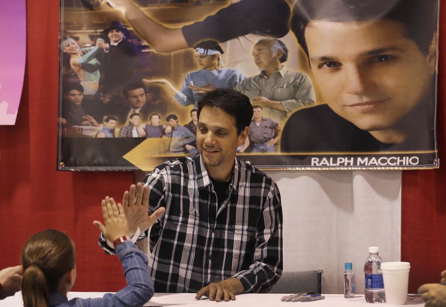 Actor Ralph Macchio, who played the Karate Kid, high-fives Sage Fauteux at the Motor City Comic Con at the Suburban Collection Showcase, Friday, May 15, 2015, in Novi, Mich. The three-day pop-culture extravaganza that gets underway Friday will welcome to the Suburban Collection Showplace in Novi dozens of celebrities from the worlds of TV, film and beyond as well as thousands of fans. Motor City Comic Con also brings in comic book and multimedia dealers who offer merchandise, including comic books, art, T-shirts and movie memorabilia. (AP Photo/Carlos Osorio)