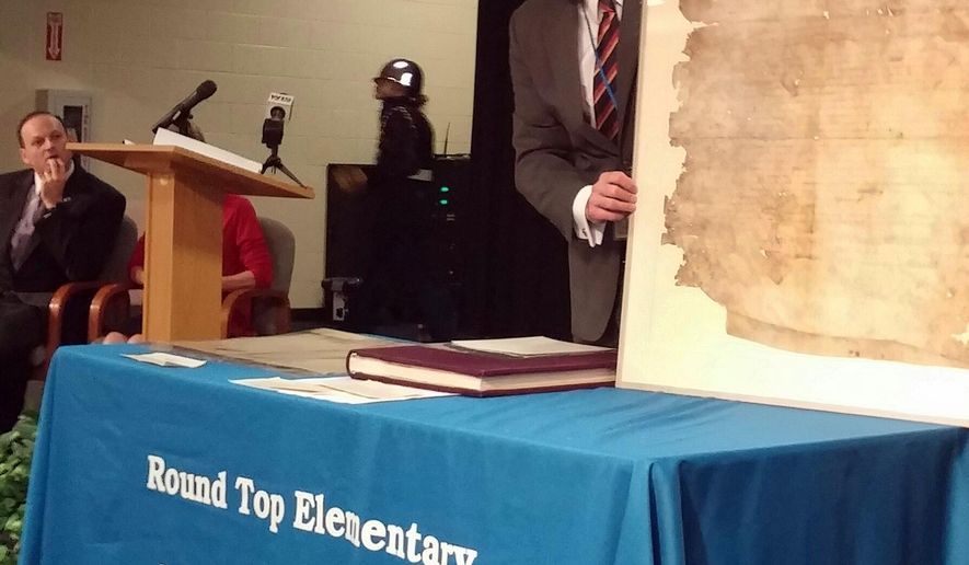 In this image provided by the SC Dept of Archives & History, SCAs Attorney General Alan Wilson,left, looks on, SC Department of Archives and History director Eric Emerson shows students at Round Top Elementary South Carolina’s original copy of the Bill of Rights, Friday, May 15, 2015, in Blythewood, S.C. (SC Dept of Archives & History via AP)