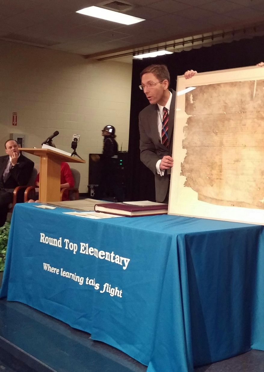 In this image provided by the SC Dept of Archives & History, SCAs Attorney General Alan Wilson,left, looks on, SC Department of Archives and History director Eric Emerson shows students at Round Top Elementary South Carolina’s original copy of the Bill of Rights, Friday, May 15, 2015, in Blythewood, S.C. (SC Dept of Archives & History via AP)