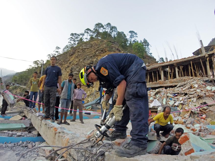 In this May 12, 2015 photo provided by the U.S. Agency for International Development's Disaster Assistance Response Team, a member of the Fairfax County Fire and Rescue Department's team helps rescue a woman from a four-story building that collapsed in this week’s earthquake in Singati, a mountain village in Nepal. Tuesday’s temblor was an aftershock to the April 25 main Gorkha earthquake that’s killed more than 8,000 people. The Disaster Assistance Response Team included urban search and rescuers from Los Angeles County and Fairfax County, Va. (USAID Disaster Assistance Response Team via AP)