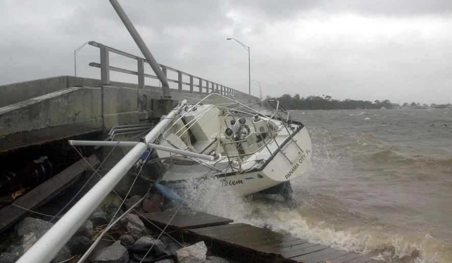 FILE - In this Sept. 16, 2004 file photo, waves crash against a sailboat lodged under a bridge in Fort Walton Beach, Fla., after Hurricane Ivan struck the gulf coast. Federal regulators believe a persistent oil spill in the Gulf of Mexico that began after a drilling platform was toppled during Hurricane Ivan in 2004 will continue for 100 years or more if left unchecked, according to estimates obtained by The Associated Press that provide new details about the extent of the problem. (AP Photo/John Bazemore, File)