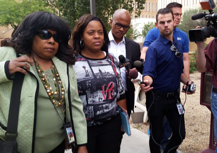 Defense attorney Valeria Llewellyn, left, and Shanesha Taylor leave a downtown Phoenix courthouse surrounded by media on Friday, May 15, 2015. Taylor, who left her two young sons alone in a hot car during a job interview in March 2014, was sentenced to 18 years of supervised probation. (AP Photo/Terry Tang)