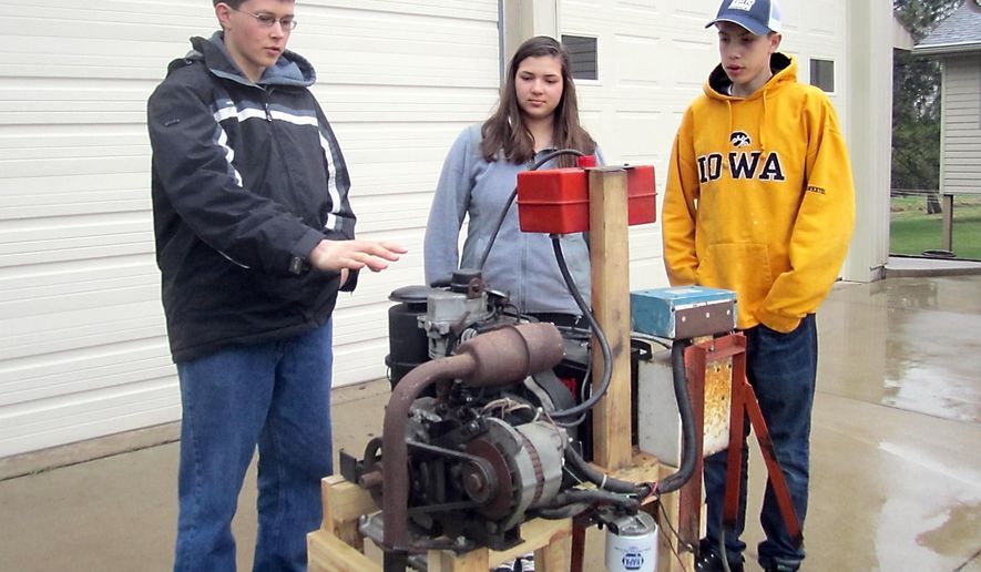 ADVANCE FOR USE MONDAY, MAY 18, 2015 - In this photo taken April 24, 2015, Brian Prchal, left, describes how the biodiesel engine he created compares to regular diesel in a one-cylinder engine in Montgomery, Minn., as Anna Prchal and Tyler Fromm look on. The students are participating in 4-H Science of Agriculture Challenge through the University of Minnesota Extension Service. (Nancy Madsen/The Free Press via AP)