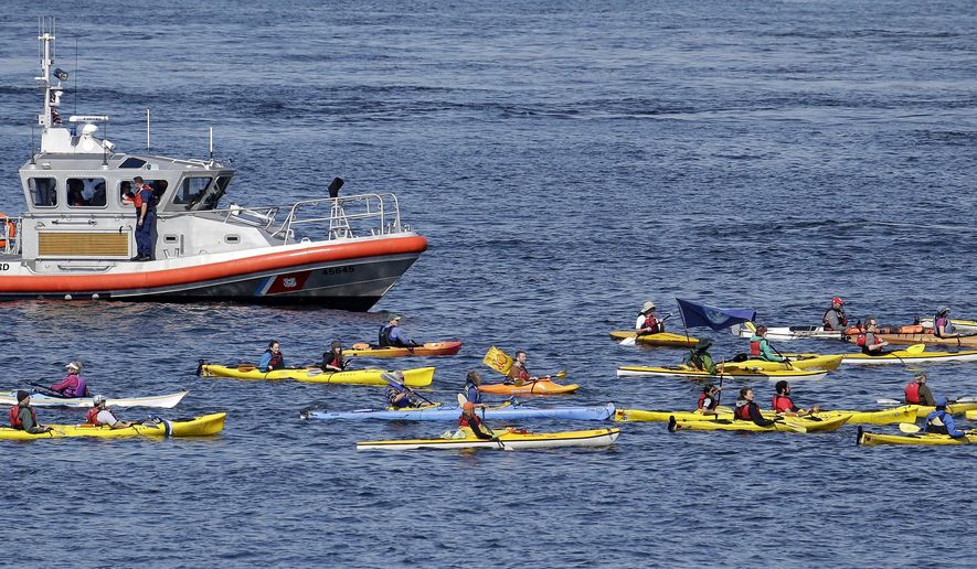 A small flotilla of kayakers protesting the oil drilling rig Polar Pioneer are followed by a U.S. Coast Guard boat Thursday, May 14, 2015, in Elliott Bay in Seattle. The rig is the first of two drilling rigs Royal Dutch Shell is outfitting for oil exploration and was towed to the Port of Seattle site despite the city's warning that it lacks permits and threats by kayaking environmentalists to paddle out in protest. (AP Photo/Elaine Thompson)