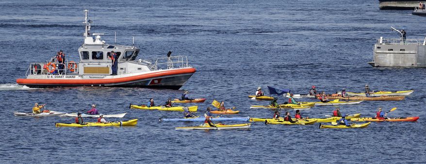 A small flotilla of kayakers protesting the oil drilling rig Polar Pioneer are followed by a U.S. Coast Guard boat Thursday, May 14, 2015, in Elliott Bay in Seattle. The rig is the first of two drilling rigs Royal Dutch Shell is outfitting for oil exploration and was towed to the Port of Seattle site despite the city's warning that it lacks permits and threats by kayaking environmentalists to paddle out in protest. (AP Photo/Elaine Thompson)