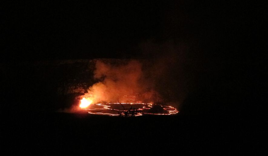 In this Saturday, May 9, 2015 photo, molten rock lights up the night as it spews into a lake of lava near the summit of Kilauea volcano on Hawaii's Big Island. The lava lake had reached a record high level on May 8 and then began descending, making scientists wonder where the molten rock will go next. (AP Photo/Cathy Bussewitz)