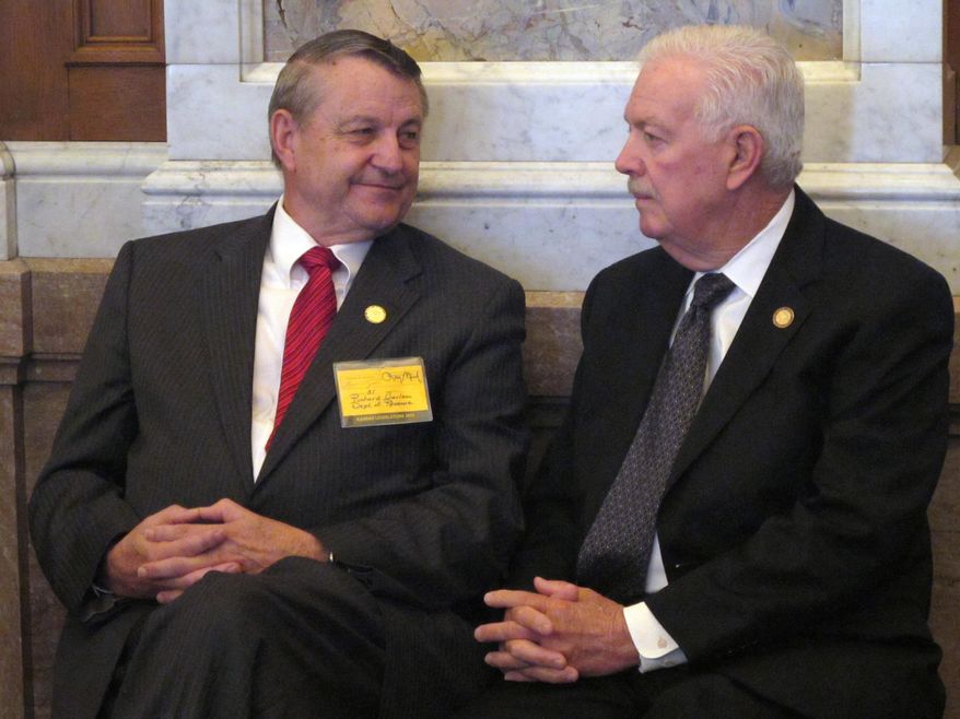 In this Friday, May 15, 2015 photo, Richard Carlson, left, legislative liaison for the Kansas Department of Revenue, visits with state House Speaker Ray Merrick during a debate in the chamber on tax issues at the Statehouse in Topeka, Kan. Carlson is a former House Taxation Committee chairman. (AP Photo/John Hanna)