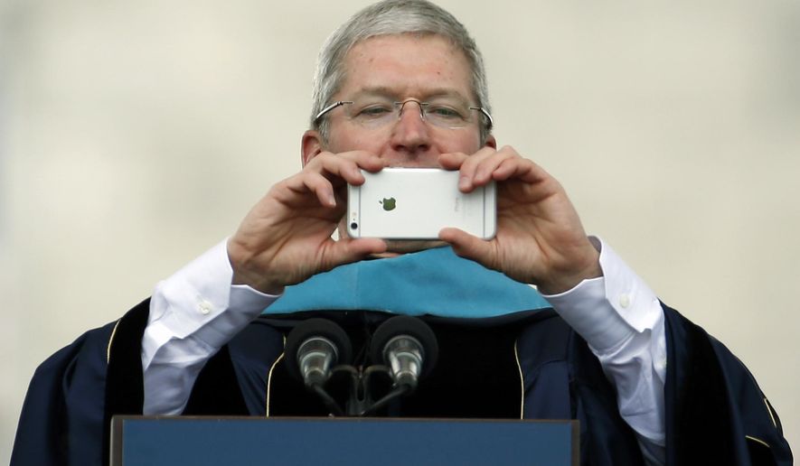 Apple CEO Tim Cook takes a picture with his iPhone while addressing graduates during George Washington University's commencement exercises on the National Mall, Sunday, May 17, 2015 in Washington. The university awarded Cook with an honorary doctorate of public service. (AP Photo/Alex Brandon)