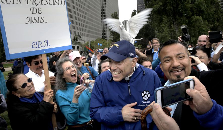 In this Saturday, May 16, 2015 photo, a dove from a supporter lands on the head of San Francisco Archbishop Salvatore Cordileone during a picnic at Sue Bierman Park in San Francisco. Hundreds turned out for a "family support picnic" held for Cordileone, who is the subject of heated debate over policy changes for Catholic high school teachers. (Michael Macor/San Francisco Chronicle via AP)