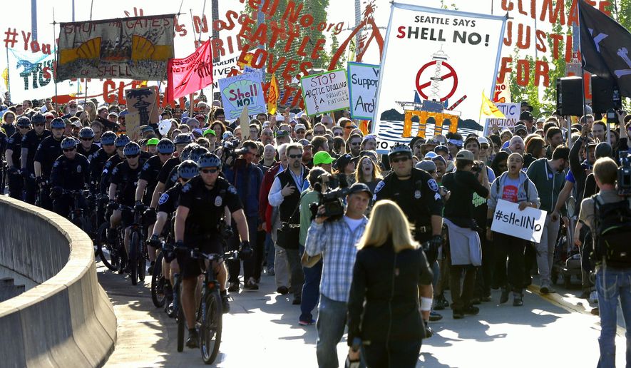 Protesters accompanied by Seattle police march at the Port of Seattle, Monday, May 18, 2015, in Seattle. Demonstrators opposed to Arctic oil drilling were showing opposition to a lease agreement between Royal Dutch Shell and the Port to allow some of Shell's oil drilling equipment to be based in Seattle. (AP Photo/Ted S. Warren)