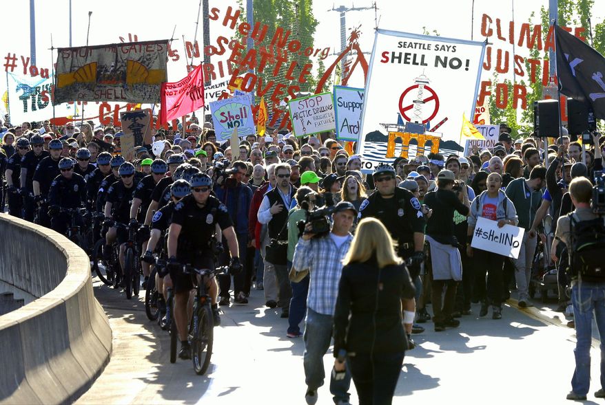 Protesters accompanied by Seattle police march at the Port of Seattle, Monday, May 18, 2015, in Seattle. Demonstrators opposed to Arctic oil drilling were showing opposition to a lease agreement between Royal Dutch Shell and the Port to allow some of Shell's oil drilling equipment to be based in Seattle. (AP Photo/Ted S. Warren)