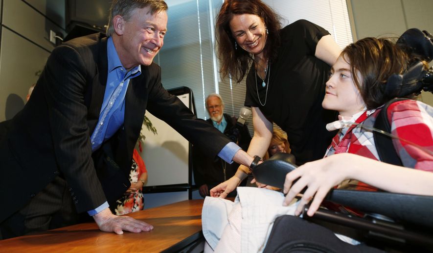 Colorado Governor John Hickenlooper, left, congratulates 14-year-old Jack Splitt, right, as his mother, Stacey Linn, looks on after the governor signed a bill named after the Wheat Ridge, Colo., teen to crack down on the state's medical marijuana industry Monday, May 18, 2015, in southeast Denver. The bill includes caregiver registration requirements and additional oversight for doctors who recommend marijuana for "severe pain." In addition, students who use medical cannabis, such as Splitt for his severe cerebral palsy, will be able to treat themselves on school grounds with the implementation of the bill's provisions. (AP Photo/David Zalubowski)