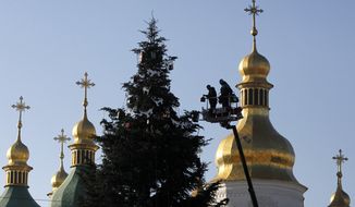 Workers decorate a New Year tree, in front of the St. Sophia Cathedral in central Kiev, Ukraine, Monday, Dec. 15, 2014. New Year is widely celebrated as the most popular holiday in Ukraine with the Orhodox Christmas being celebrated on Jan. 7. (AP Photo/Sergei Chuzavkov)