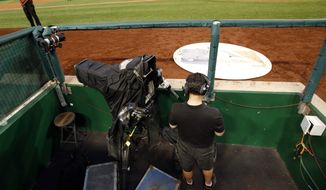 A MASN network videographer checks his phone after technical problems forced the network to use a different feed for several innings of a baseball game between the Washington Nationals and the Philadelphia Phillies at Nationals Park Saturday, Aug. 2, 2014, in Washington. (AP Photo/Alex Brandon) **FILE**