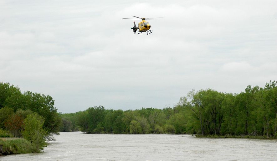 A helicopter searches the South Platte River just west of the Buffalo Bill Road Bridge, Tuesday, May 19, 2015, in North Platte, Neb. Authorities are searching the river in western Nebraska, looking for two people who reportedly drove into the rushing water the night before. (Joe Volcek/The Telegraph via AP)