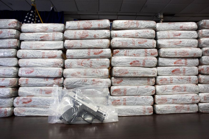 A firearm and 154 pounds of heroin worth at least $50 million are displayed at a Drug Enforcement Administration news conference, Tuesday, May 19, 2015 in New York. The DEA called the heroin seizure its largest ever in New York state. Officials said on Tuesday that most of the drugs were found in an SUV in the Bronx following a wiretap investigation. (AP Photo/Mark Lennihan)