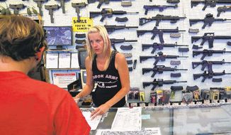 An employee at a gun store in Colorado assists a customer. (Associated Press) ** FILE **