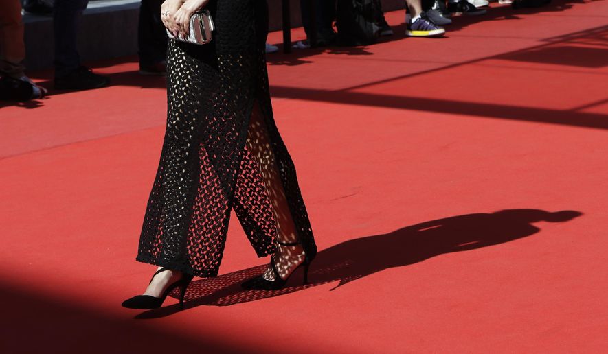 An unidentified guest walks on the red carpet as she arrives for the screening of the film La Loi du Marche (The Measure of a Man) at the 68th international film festival, Cannes, southern France, Monday, May 18, 2015. (AP Photo/Lionel Cironneau)
