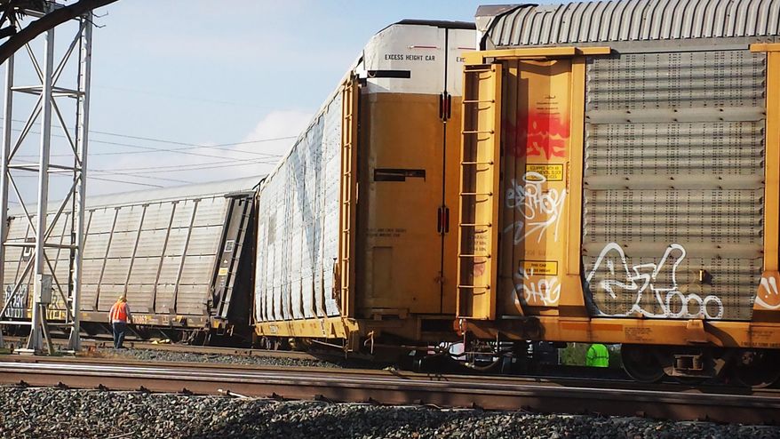 Railroad personnel look over a derailed freight train Tuesday, May 19, 2015, in Jurupa Valley near Riverside, Calif. Officials say nobody was hurt when the Union Pacific freight train carrying automobiles derailed in Riverside County early Tuesday morning. (Tom Bray/The Press-Enterprise via AP) MAGS OUT; MANDATORY CREDIT