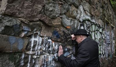 In this photo taken on Wednesday, May 13, 2015, Shmuel Levin, the chairman of the Jewish religious Community of Vilnius and Lithuania, leans against a wall of the power substation built of tombstones from a Jewish cemetery in Vilnius, Lithuania. Tombstones from a Jewish cemetery were used to build a power substation in the 1960s. (AP Photo/Mindaugas Kulbis)